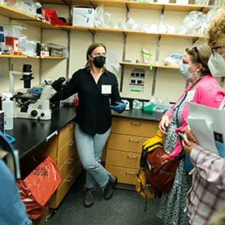 A person in a laboratory talking to a group of people
