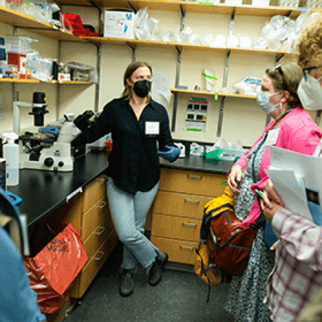A person in a laboratory talking to a group of people