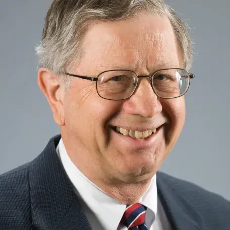 A person wearing glasses, a blazer, and a tie