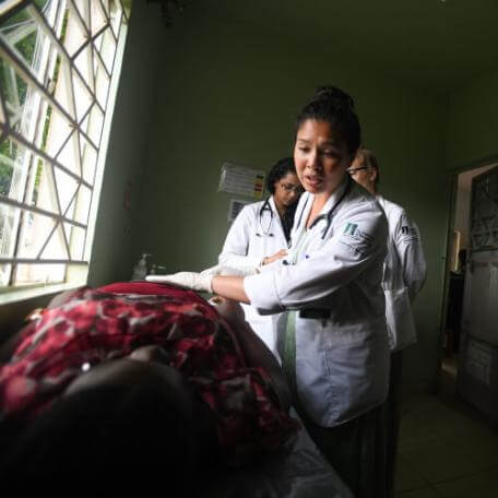 Doctor speaks to a patient on a bed in a rural clinic