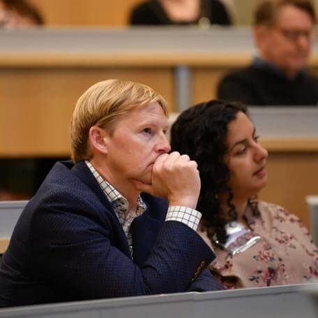 two people in a classroom listening to a speaker