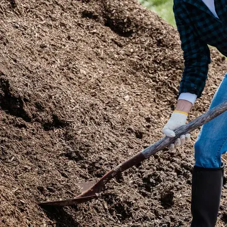 a person shoveling mulch
