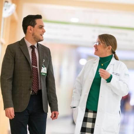 2 people facing one another talking in a hallway
