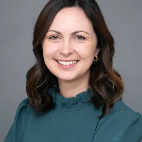 A person with brown hair wearing a blue blouse
