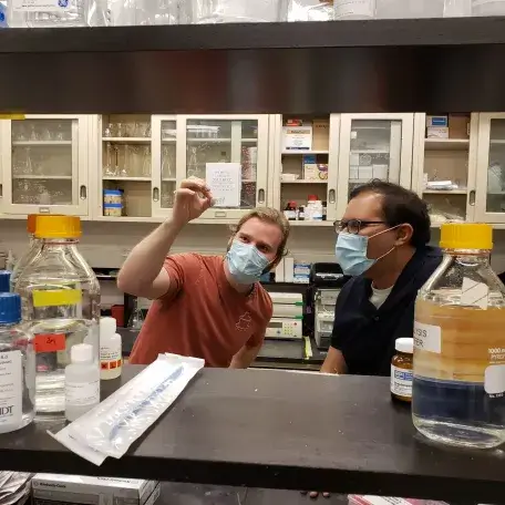 Dev Majumdar and Zach Miller inspect a small vial in their lab