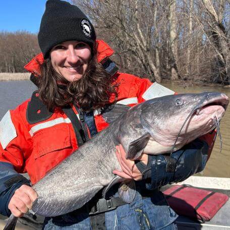Thais in a hat and life jacket holding a massive fish.