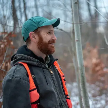 Peter Clark standing in a forest looking away from the camera