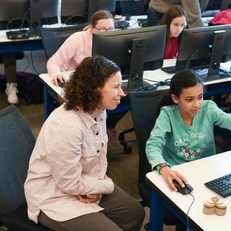 student pointing to a screen in front of a teacher