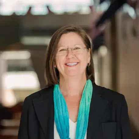 person in dark coat and green scarf smiling
