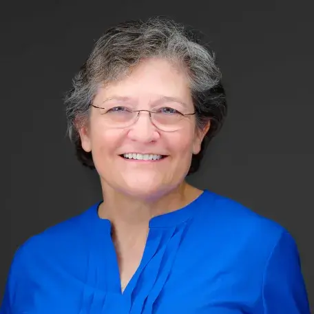 debbie ingram wearing a blue shirt and facing the camera against a black background