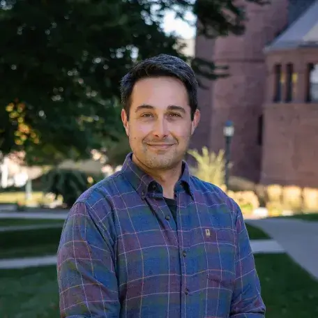 A headshot of a man wearing a purple shirt