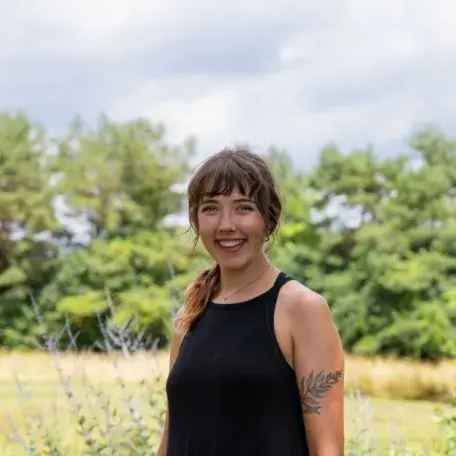Ayana is smiling looking at the camera and trees on background