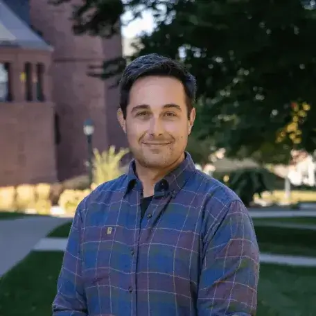 A headshot of a man wearing a purple shirt