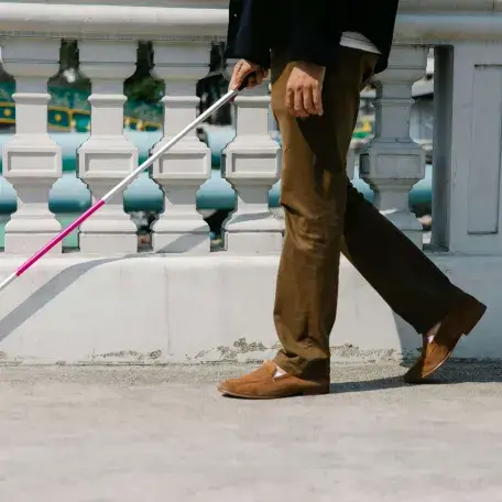 A person with a Deafblind cane walks along a path