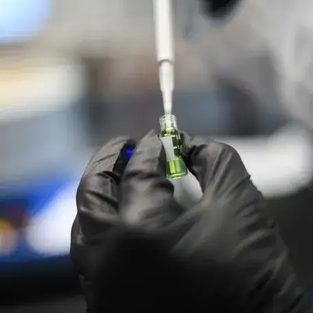 gloved hand holding a test tube near a lab bench
