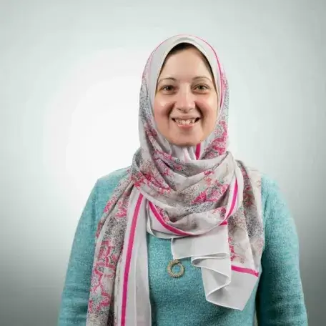 Person in pink and white head scarf and turquoise sweater.