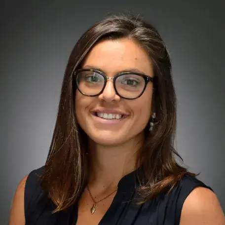 olive skinned woman with long dark her, dark rimmed glasses and dark sleeveless top
