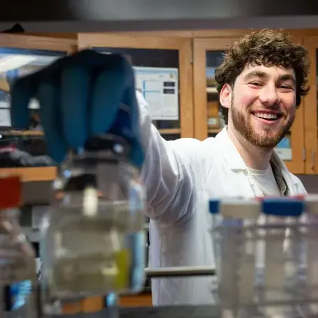 scientist reaching for chemical bottle