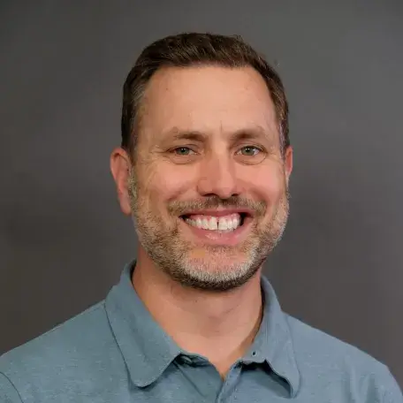 man in a blue button up shirt with light beard and short brown hair