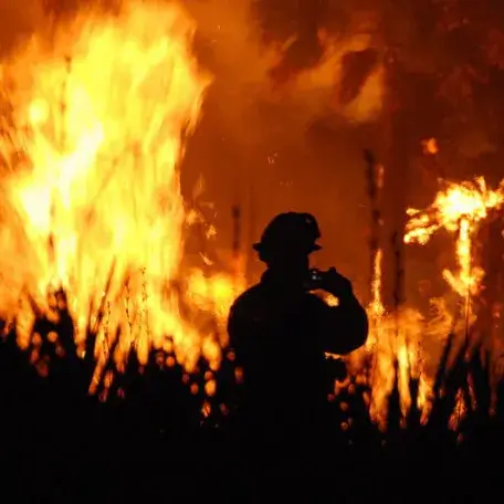 A fire with the silhouette of a fire fighter in front. 