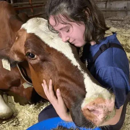 A young woman hugging a cow