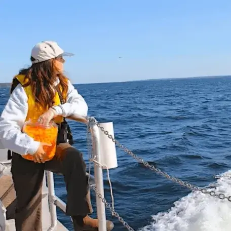 A young woman on a boat feeding seagulls cheese puffs