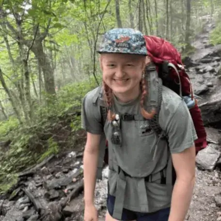 A young woman with a backpack in the woods