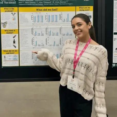 A young woman in front of a scientific poster board presentation