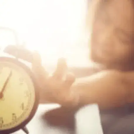 person reaching for an alarm clock