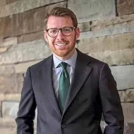 man with beard and glasses wearing a gray jacket and green tie