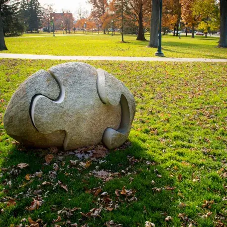 Oval stone sculpture of three puzzle pieces.