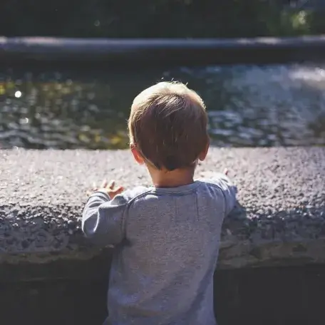 a small child looking out over a pond