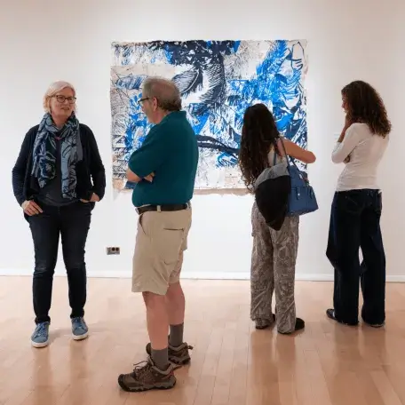 Two pairs of museum visitors look at art in the gallery.