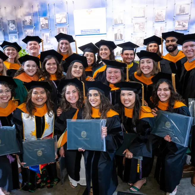 Smiling graduates showing their diplomas.
