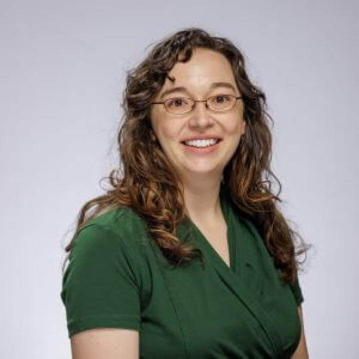Andrea in a green blouse in front of a white background.