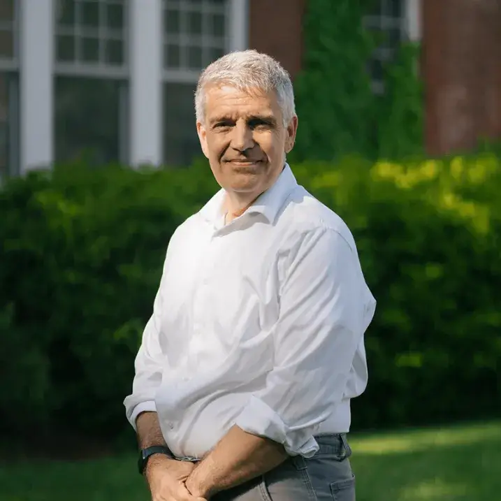 Bill smiling on a bright day, outdoors, surrounded by green