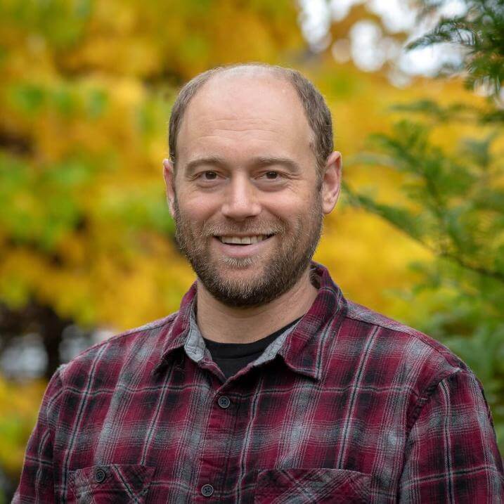 Headshot of Eric Bishop von Wettberg in plaid shirt in front of yellow trees