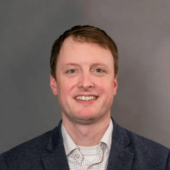 Researcher smiling posed against a grey background