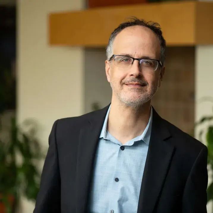 A person wearing black blazer and glasses