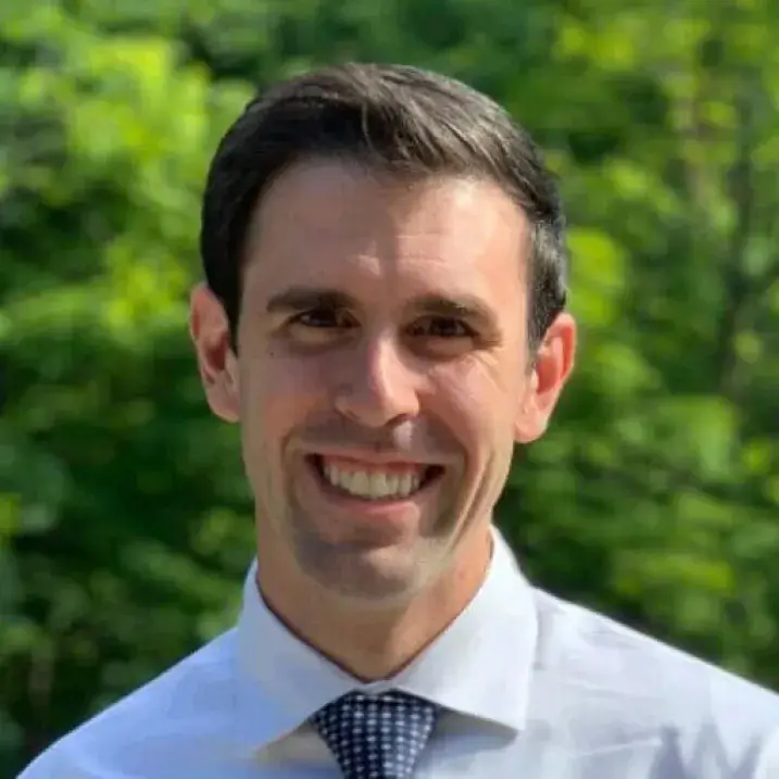 Headshot image of the researcher outdoors, posed in front of green foliage