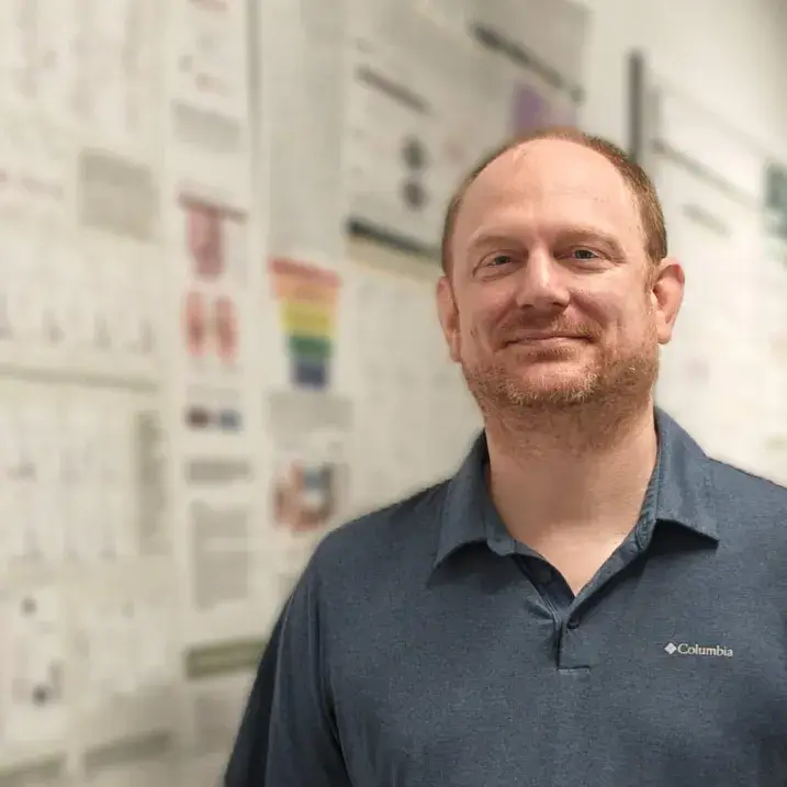 person smiling beside research poster