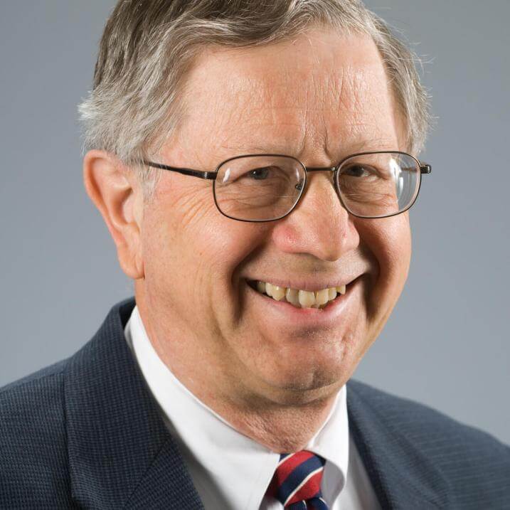 A person wearing glasses, a blazer, and a tie