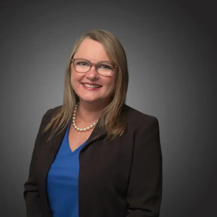 A person wearing a black blazer and  blue blouse