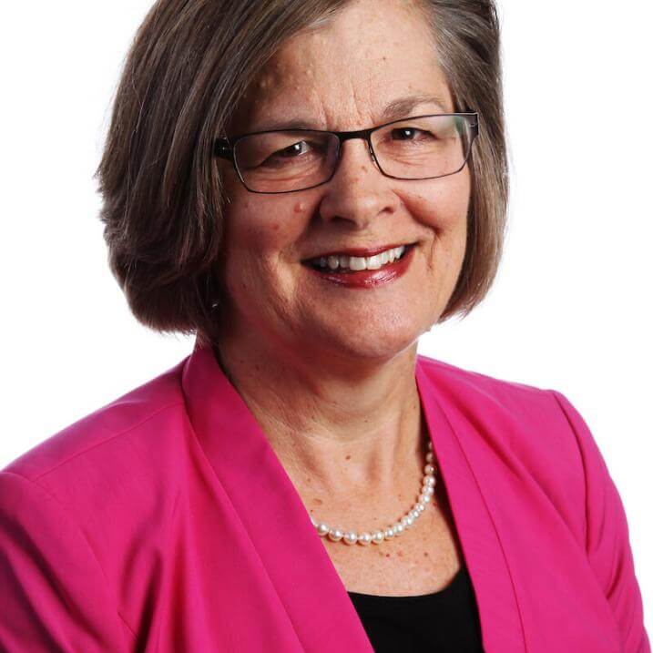 A person wearing glasses and a pink blazer