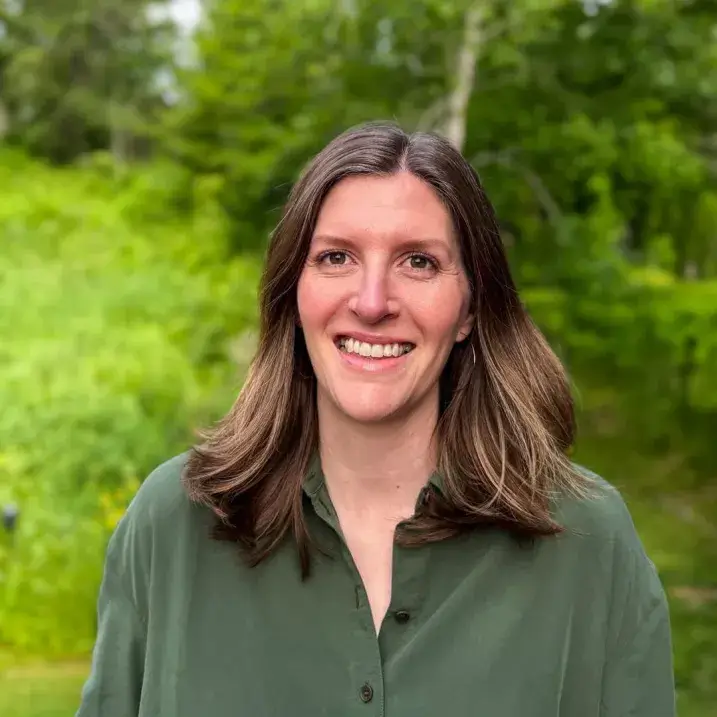 Headshot of Alayna Howard, wearing a green shirt, standing outside, smiling