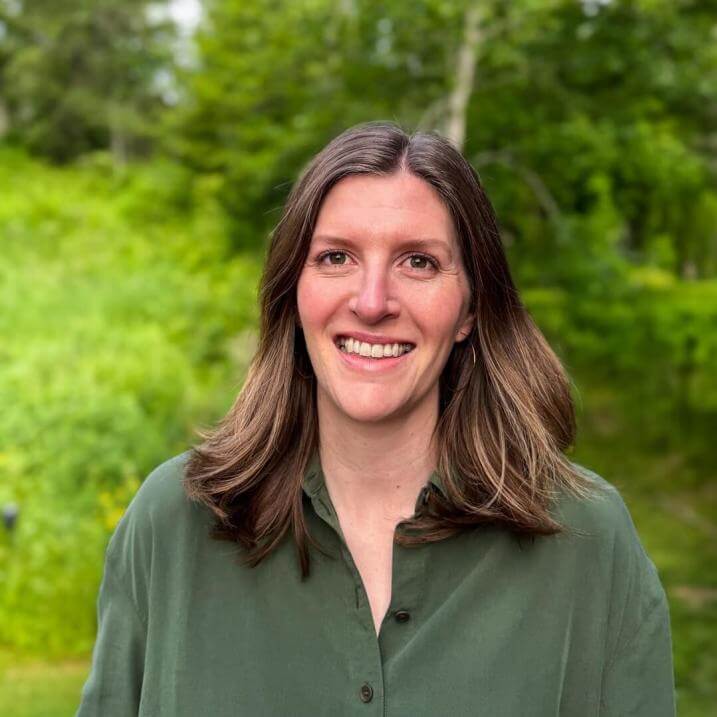 Headshot of Alayna Howard, wearing a green shirt, standing outside, smiling