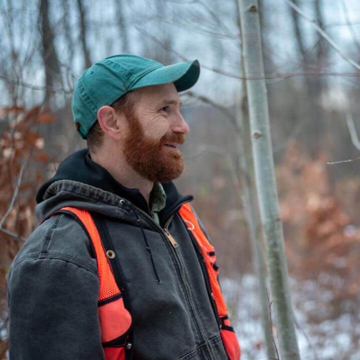 Peter Clark standing in a forest looking away from the camera
