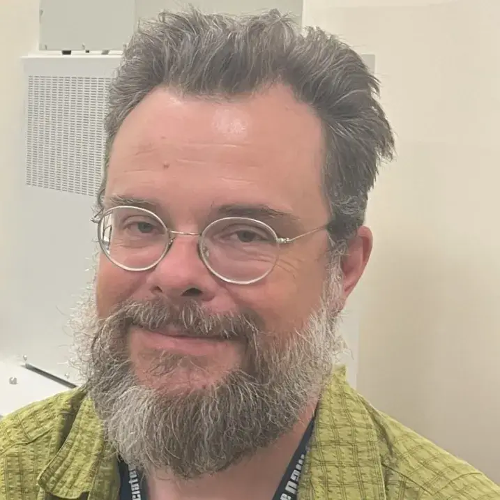 Person smiling in front of beige wall