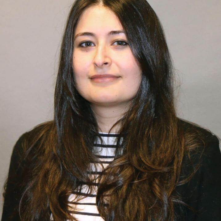 A person wearing a striped shirt and a black sweater