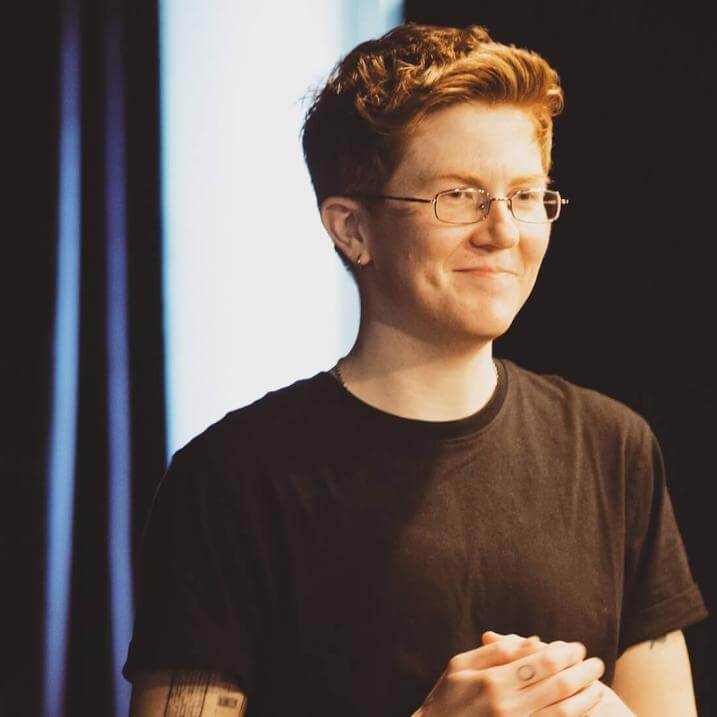 smiling person wearing glasses and black t-shirt